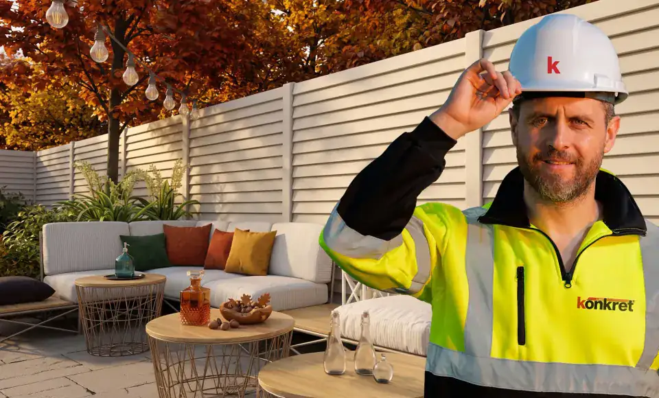 Konkret Line installer in a hard hat and high-visibility jacket in front of a finished fence