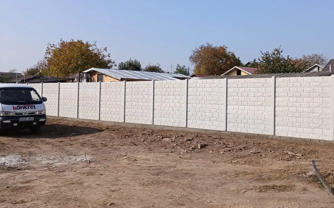 Konkret Line vehicle next to a white concrete fence with a stacked-stone relief